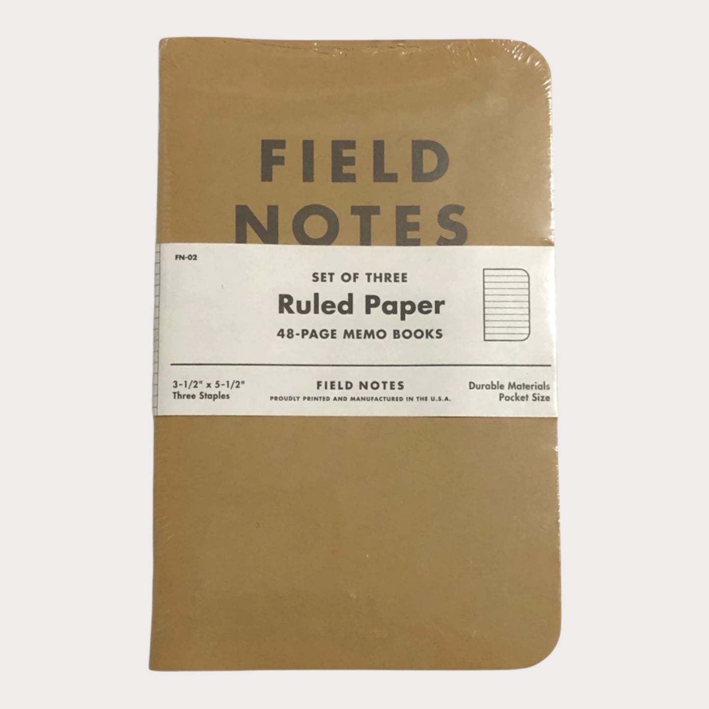 Set of three Field Notes notebooks with brown cover and white label on a light gray background