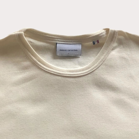 Close-up of a beige garment with a visible label on a white background