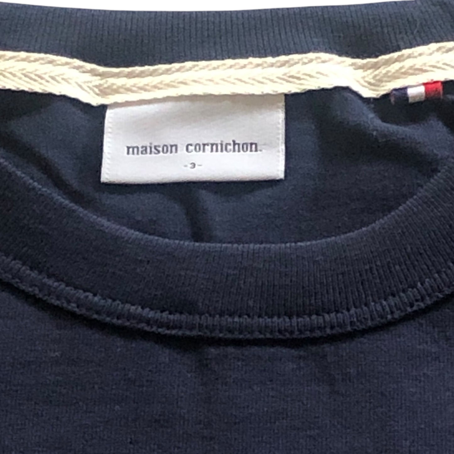 Navy blue fabric with a 'maison cornichon' label on a close-up of clothing.