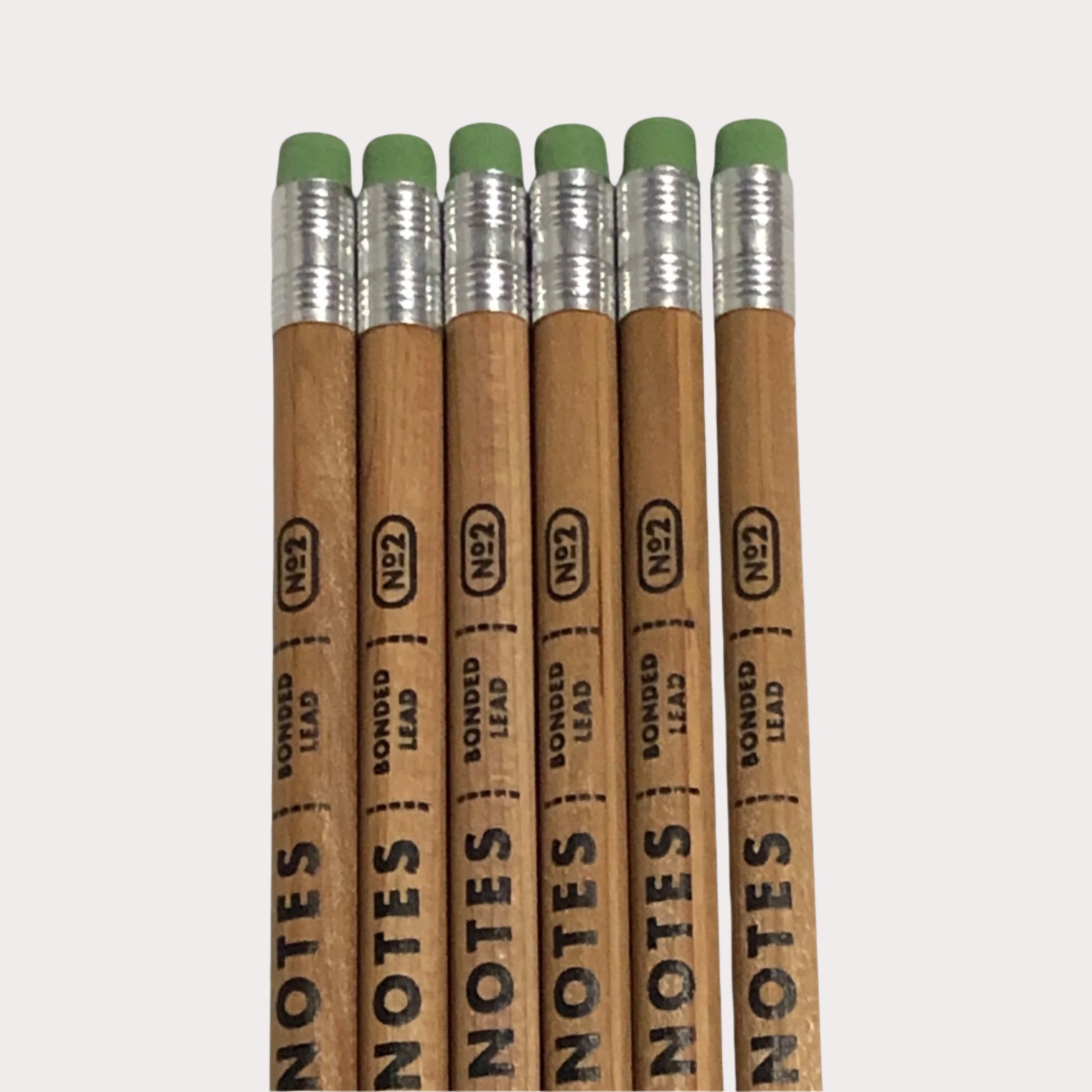 Set of six wooden pencils with green erasers and 'FIELD NOTES' branding on a white background