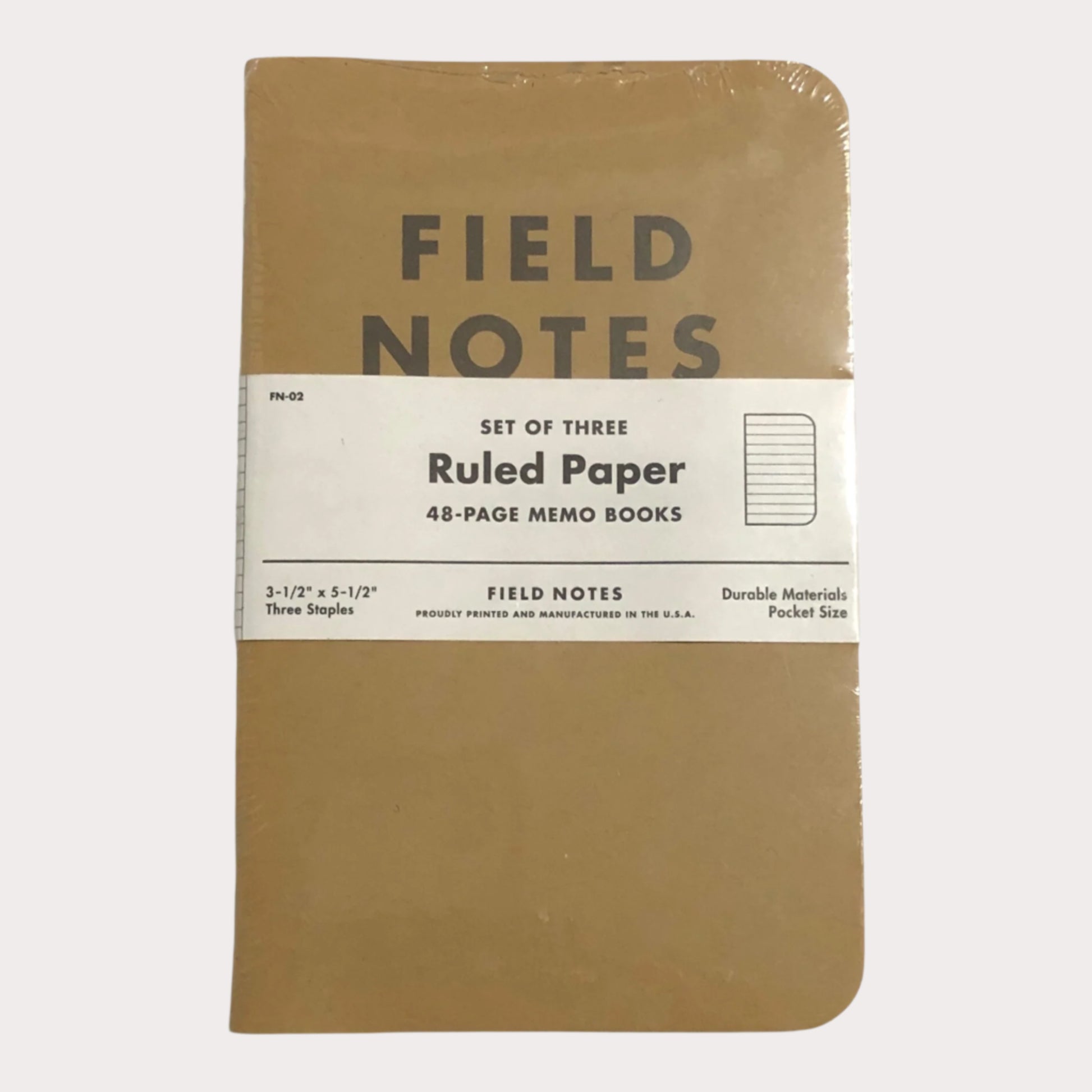 Set of three Field Notes notebooks with brown cover and white label on a light gray background