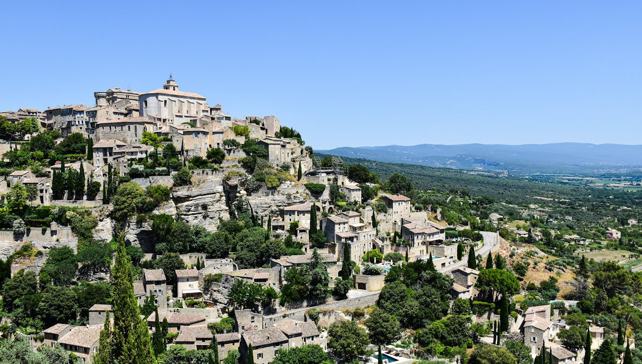 The Village of Fer à Cheval Brand perched on a hillside with greenery and clear blue sky