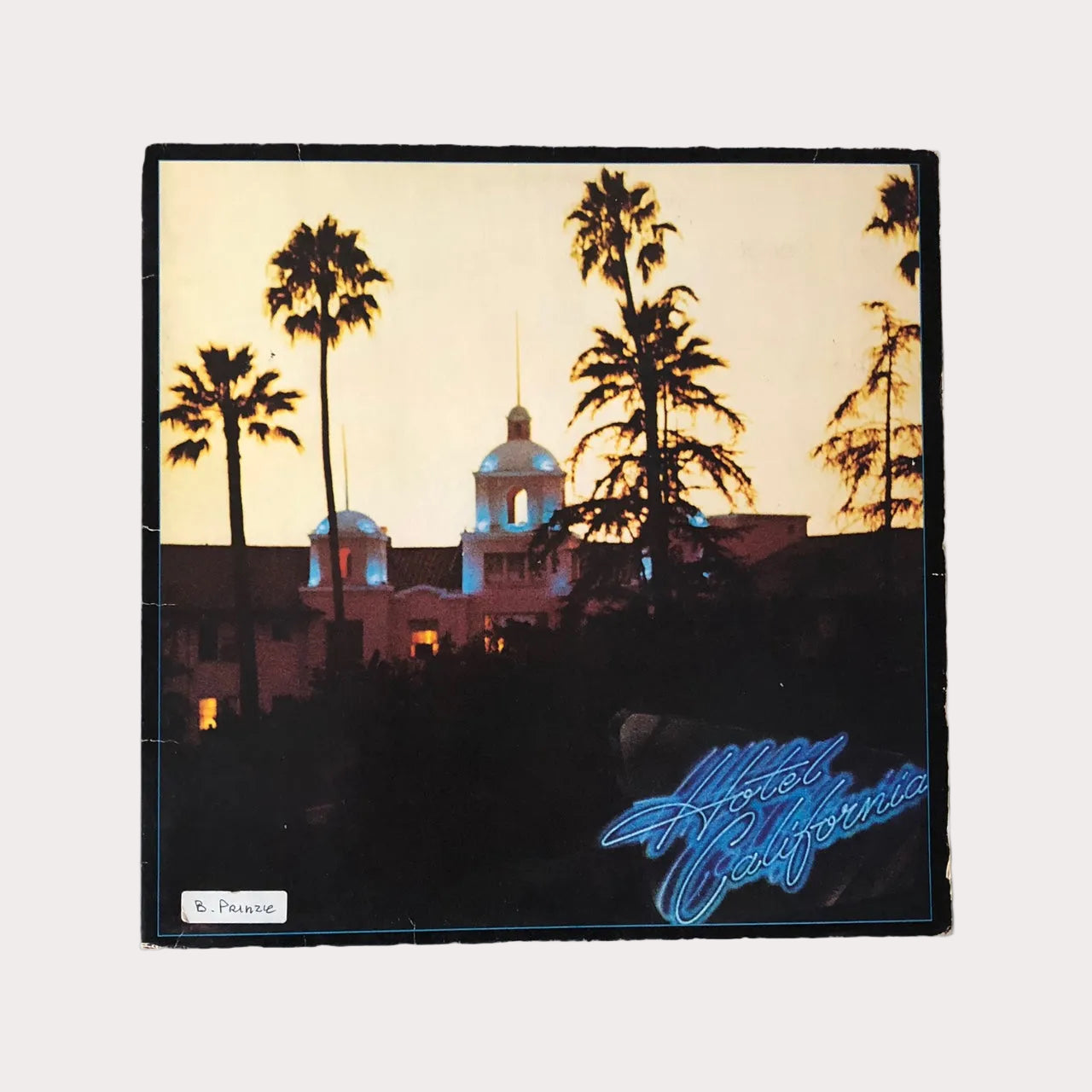 Vinyl LP record of The Eagles - Hotel California with a vintage cover featuring palm trees and a sunset.