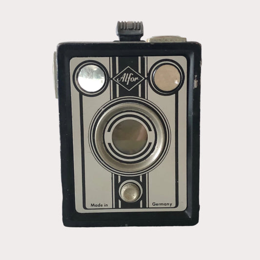 A vintage Alfor camera with a black and white striped design, featuring a lens, viewfinder, and control buttons on the top panel.